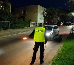 policjant daje znak latarką do zatrzymania