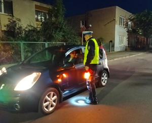 policjant stoi przy zatrzymanym pojeżdzie