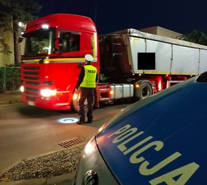 policjant stoi przy zatrzymanej cięzarówce
