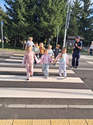 policjant przeprowadza dzieci przez jzednię