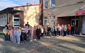 zdjęcie grupowe dzieci i policjanta przed szkoła