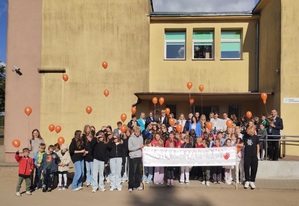 zdjecie grupowe dzieci przed szkoła, które trzymają w reku transparent na którym jest napis &quot;stop przemocy&quot;, dzieci trzymają w rękach balony