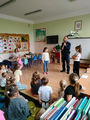 policjant pokazuje dzieciom opaske odblaskowa