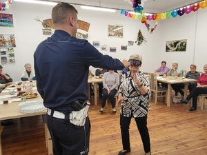 policjant na środku sali wyciąga rekeę do kobiety, która ma na sobie założone alkogoogle