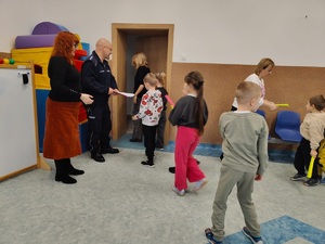 policjant stoi przy drzwiach i rozdaje odblaski