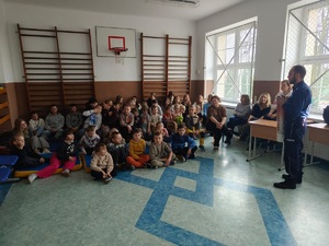 policjant stoi przed dziecmi i prowadzi prelekcje