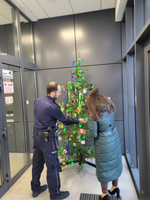 przy choince stoi policjant i jeszcze jedna osoba