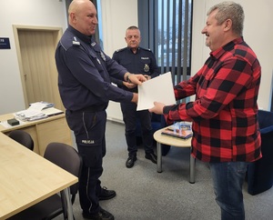 Komendant podaje rękę jubilatowi i wręcza mu list