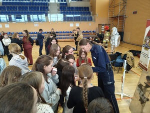 Policjantka rozdaje uczestnikom broszury informacyjne