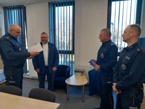 komendat odczytuje list gratulacyjny, na zdjeciu cztery osoby