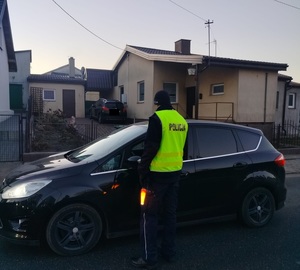 policjant stojący przy zatrzymanym pojeździe