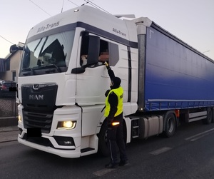 policjant stoi przy pojezdzie i kontroluje stan trzexwości kierowcy