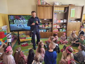 policjant przy pomocy tuby pokazuje dzieciom jak wygladają odblaski