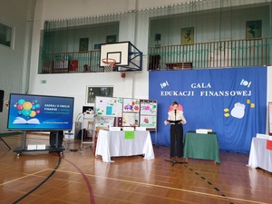 zdjecie przedstawia scenę przygotowaną do gali, na ktorej stoi prowadząca