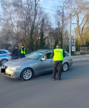 policjant na drodze stoi przy zatrzymanym kierowcy