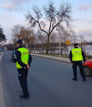 dwóch policjantów stoi na drodze i zatrzymują pojazdy