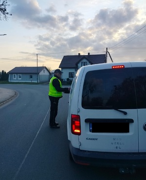 policjant na drodze stoi przy zatrzymanym kierowcy i bada kierowcy stan trzexwości