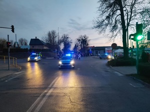 trzy radiowozy stoja na skrzyzowaniu i zabezpieczają wjazdy, na które wchodzą patnicy