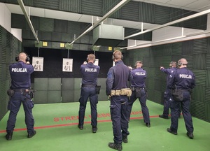 czterech policjantów stoli na linii i oddaja strzały,, a za nimi instruktorzy