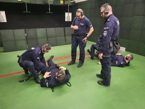 policjani udzielają pomocy leżących policjantom, przygląda się temu dwóch prowadzacych stzrelanie