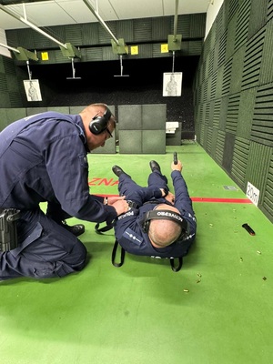 jednek z policjantówudziela pomocy poszkodowanemu , który leży na ziemi