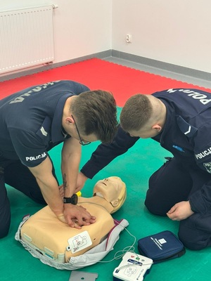 dwóch policjantów ćwiczy udzielanie pierwszej pomocy na fantomie wykonując uciski