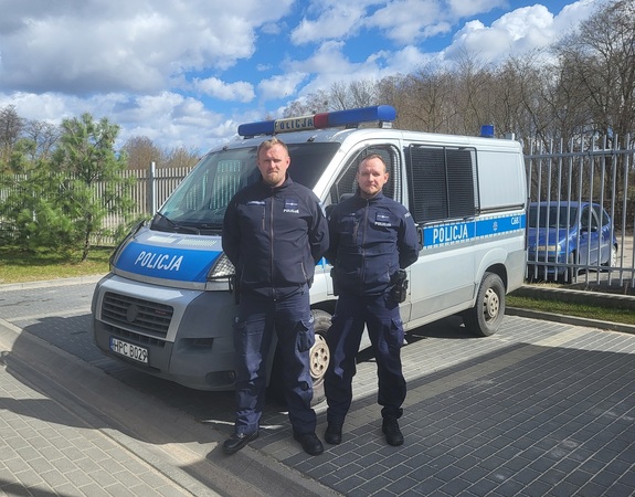 dwóch policjantów stojących na tle radiowozu