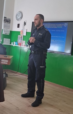 policjant stojący w klasie i prowadzący prelekcję