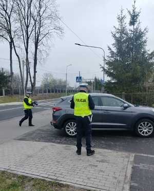 dwóch policjantów podchodzi do zatrzymanego pojazdu