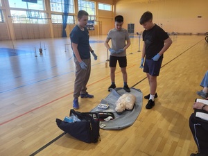 trzyosobowa druzyna stoi nad fantomem po udzielonej pomocy