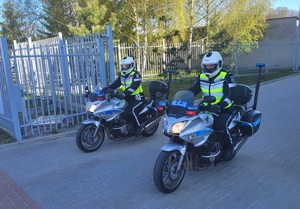 dwóch policjantów na motocyklach wyjeżdżających z terenu jednostki policji