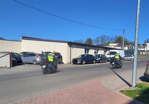 dwóch policjantów na motocyklach jadących drogą