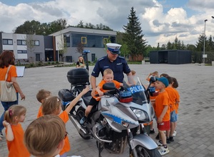 policjant stoi przy motocyklu, na którym siedzi dziecko
