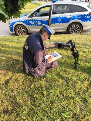 policjant siedzacy przy hulajnodze i sporządzający dokumentację