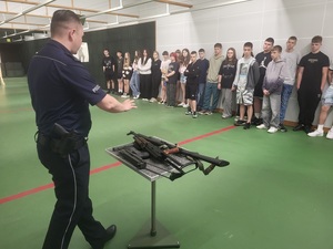 w pomieszczeniu strzelnicy, policjant prezentuje broń i prowadzi prelekcje