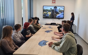 policjantka w pomieszczeniu prezentuje film zebranym uczniom