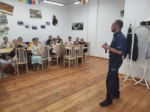 policjant stoi przed uczestnikami spotkania i prowadzi prelekcje
