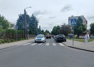 radiowóz policyjny prowadzi procesję