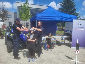 dwóch policjantów zakłada policyjny sprzet na chłopca