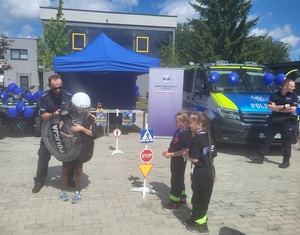 policjant pomaga jednej osobie założyć sprzet policyjny