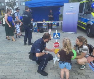 policjant pokazuje znaki drogowe dziecku