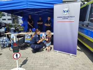 policjantka wręcza dziecku odblaski i ulotki