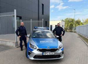 dwóch policjantow stojących obok radiowozu