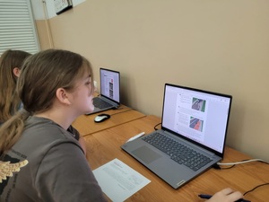 dziecko siedzi przed laptopem gdzie rozwiązuje test