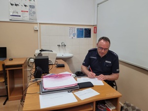 policjant siedzi przy biurku i sprawdza testy