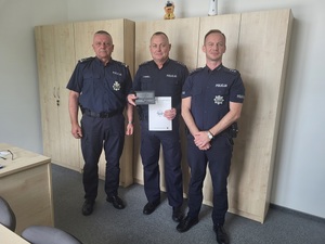 trzech policjantów, jeden z ich trzyma list oraz upominek