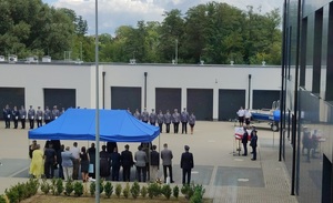 zdjecie całego placu, na którym stoją policjanci, namiot pod którym stoja goscie oraz mównica