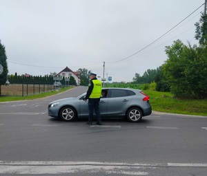 policjant stoi policjant stoi przy pojeździe i bada stan trzexwości kierowcy
