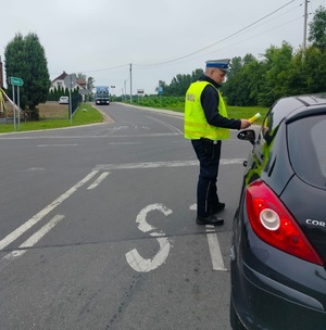 policjant stoi policjant stoi przy pojeździe i bada stan trzexwości kierowcy