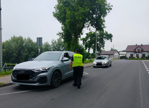 policjant stoi policjant stoi przy pojeździe i bada stan trzexwości kierowcy